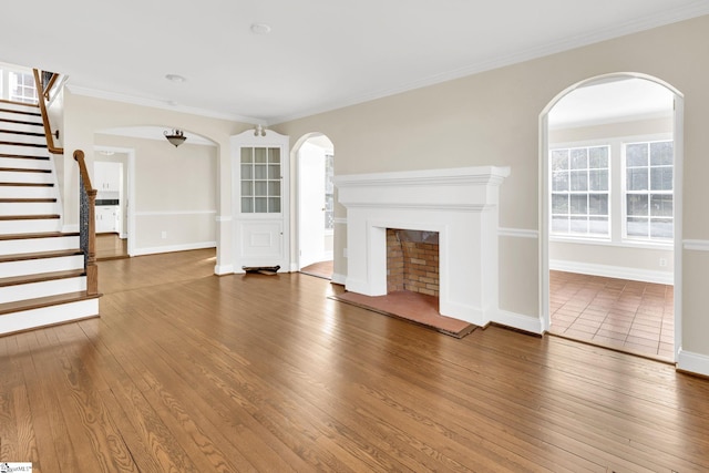 unfurnished living room with crown molding, baseboards, stairway, a fireplace, and hardwood / wood-style flooring