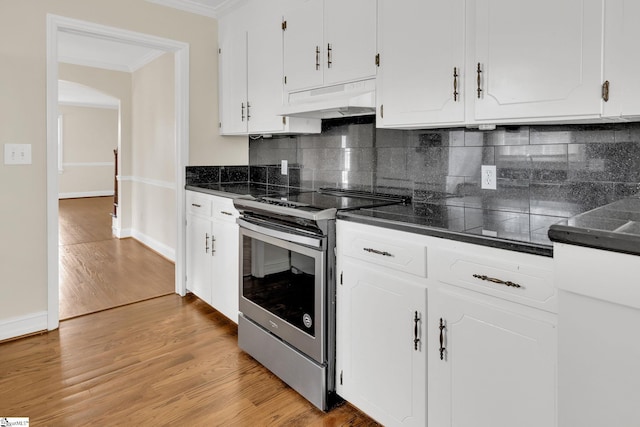 kitchen with under cabinet range hood, dark countertops, stainless steel range with electric stovetop, and crown molding