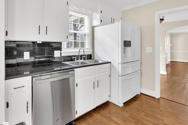 kitchen with dark countertops, a sink, ornamental molding, and stainless steel dishwasher