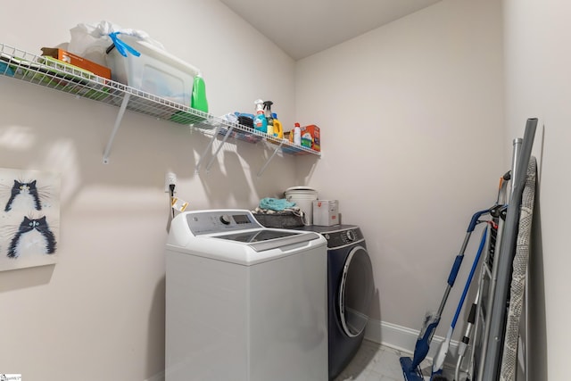 clothes washing area with washer and dryer, baseboards, marble finish floor, and laundry area