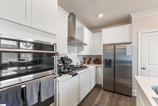 kitchen with light countertops, white cabinets, dark wood-type flooring, appliances with stainless steel finishes, and wall chimney exhaust hood