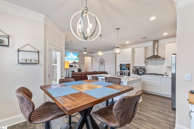 dining room with baseboards, light wood-style flooring, recessed lighting, ornamental molding, and ceiling fan with notable chandelier