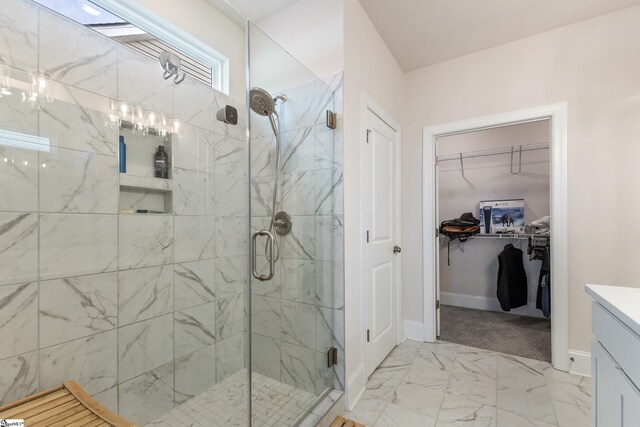 bathroom with a walk in closet, marble finish floor, a stall shower, baseboards, and vanity