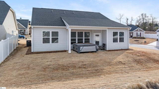 back of house featuring a hot tub, roof with shingles, central AC, and fence