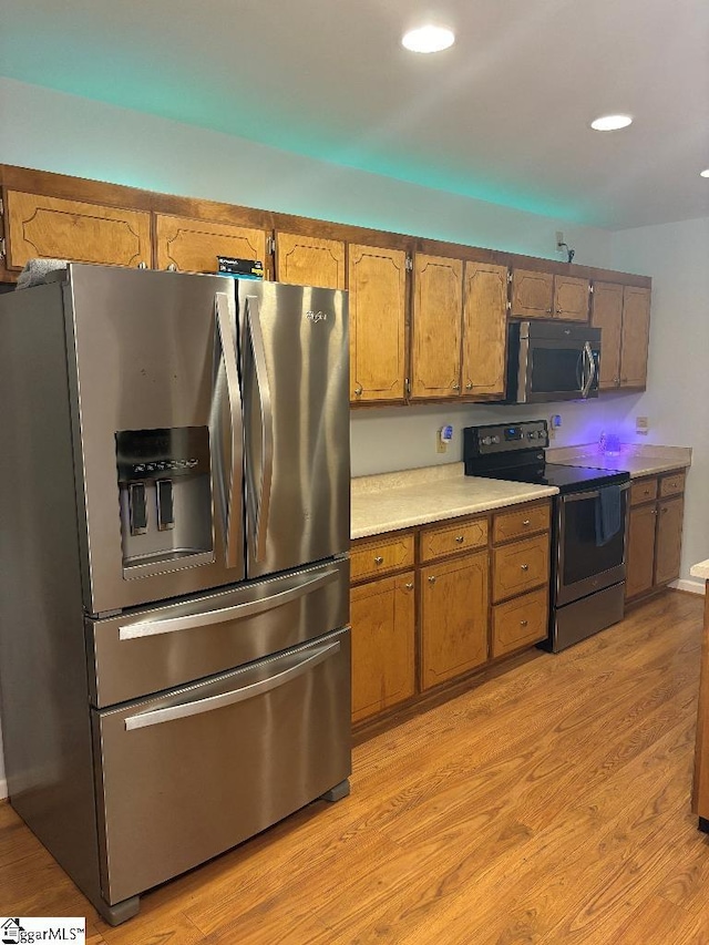 kitchen with light countertops, light wood-style flooring, brown cabinetry, and stainless steel appliances