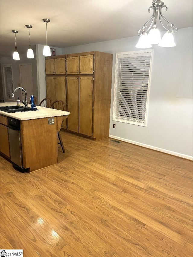 kitchen with a sink, pendant lighting, brown cabinetry, and light wood finished floors