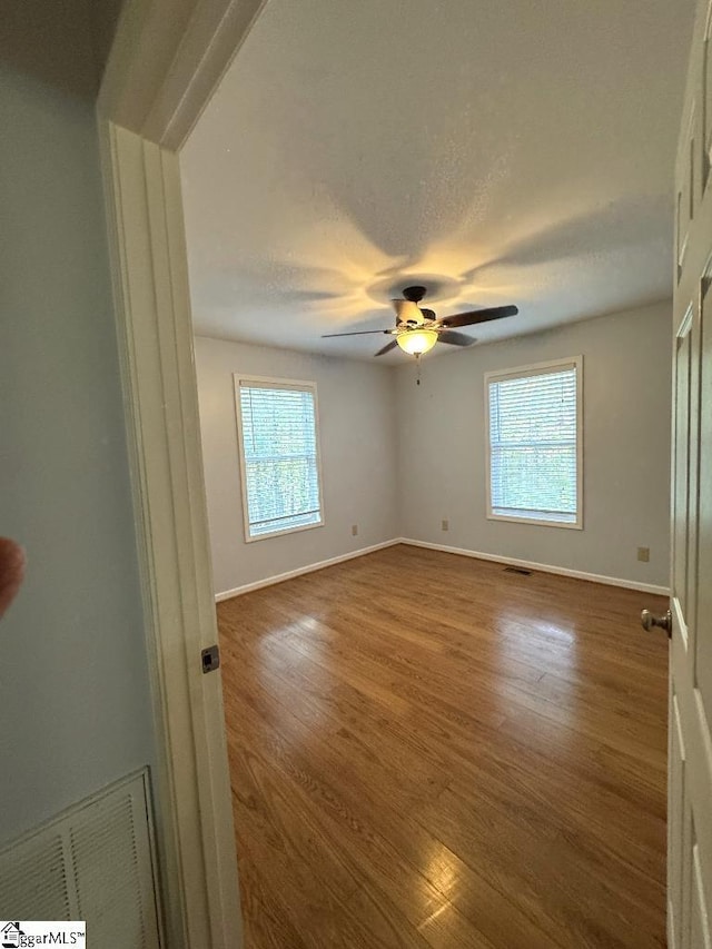 unfurnished bedroom with a textured ceiling, wood finished floors, visible vents, and baseboards