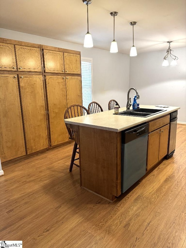 kitchen featuring a kitchen island with sink, a sink, light wood-style flooring, and stainless steel dishwasher