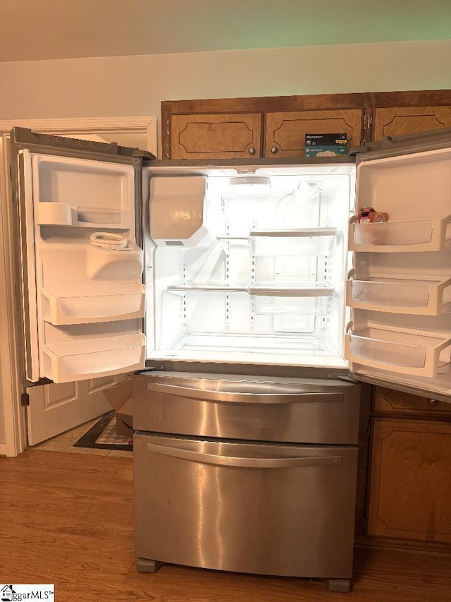 details with wood finished floors, brown cabinetry, and freestanding refrigerator