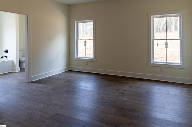 empty room featuring dark wood-type flooring and baseboards