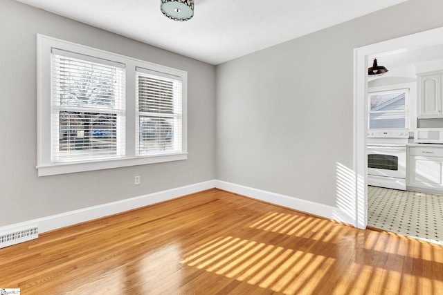 unfurnished room with light wood-type flooring, visible vents, and baseboards