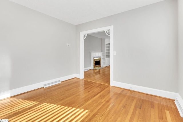 unfurnished room featuring visible vents, baseboards, light wood-style floors, and a high end fireplace