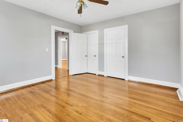 unfurnished bedroom featuring a ceiling fan, baseboards, two closets, and light wood-type flooring