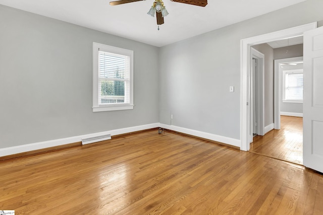 spare room featuring a ceiling fan, baseboards, visible vents, light wood finished floors, and attic access