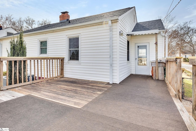 back of property featuring roof with shingles, a deck, and a chimney