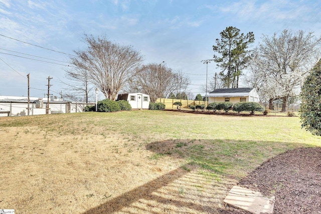 view of yard with an outdoor structure, a storage unit, and fence