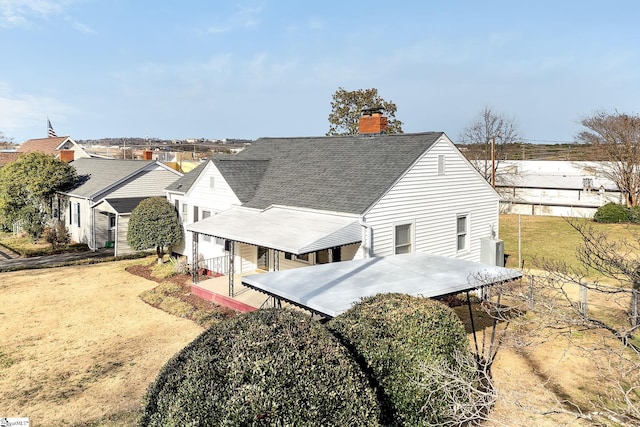 rear view of property with a chimney and a shingled roof