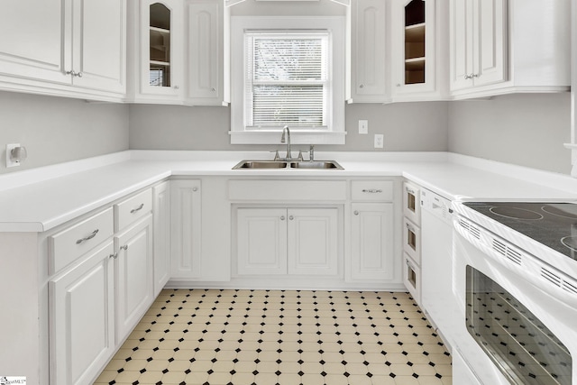 kitchen featuring white electric range oven, a sink, light countertops, glass insert cabinets, and white cabinetry