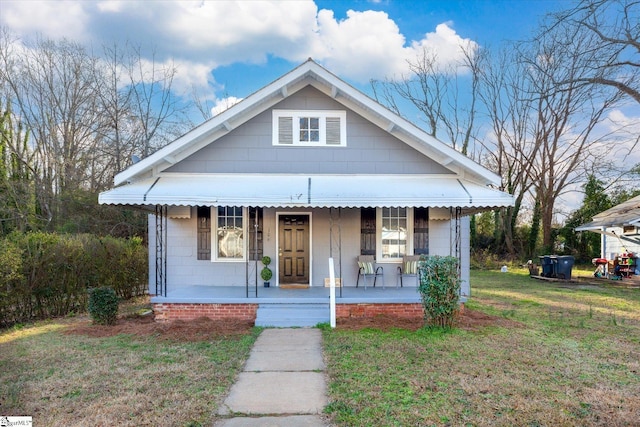 bungalow-style home featuring a porch, concrete block siding, and a front lawn