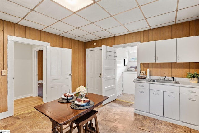 dining space featuring a drop ceiling and wood walls