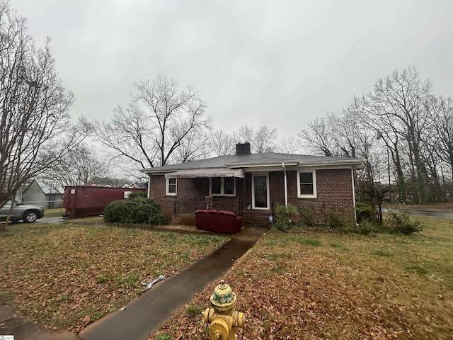 view of front of home featuring a front lawn, brick siding, and a chimney