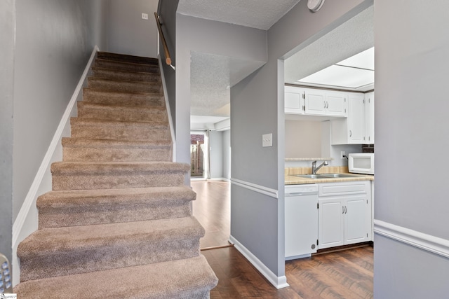 stairway featuring baseboards, a textured ceiling, and wood finished floors