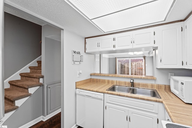 kitchen featuring white appliances, white cabinets, light countertops, and a sink