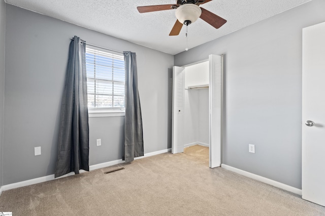 unfurnished bedroom featuring baseboards, visible vents, carpet floors, and a textured ceiling