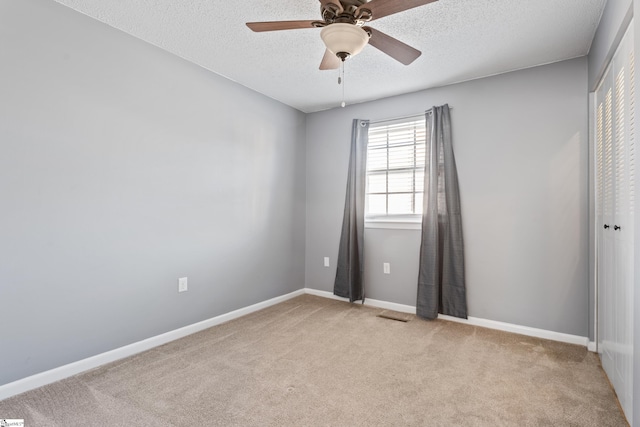 empty room featuring visible vents, baseboards, ceiling fan, a textured ceiling, and carpet flooring