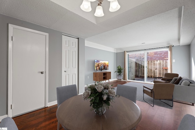 dining room with a textured ceiling, baseboards, and wood finished floors