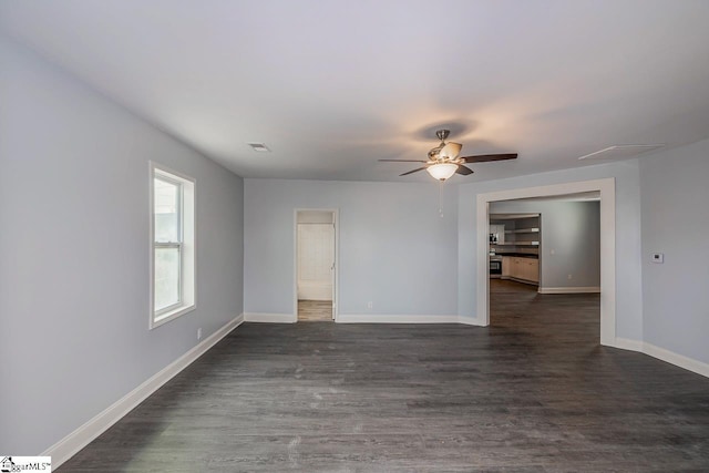 spare room featuring visible vents, a ceiling fan, dark wood-type flooring, and baseboards