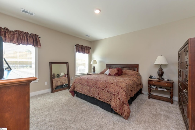 bedroom with light carpet, visible vents, and baseboards