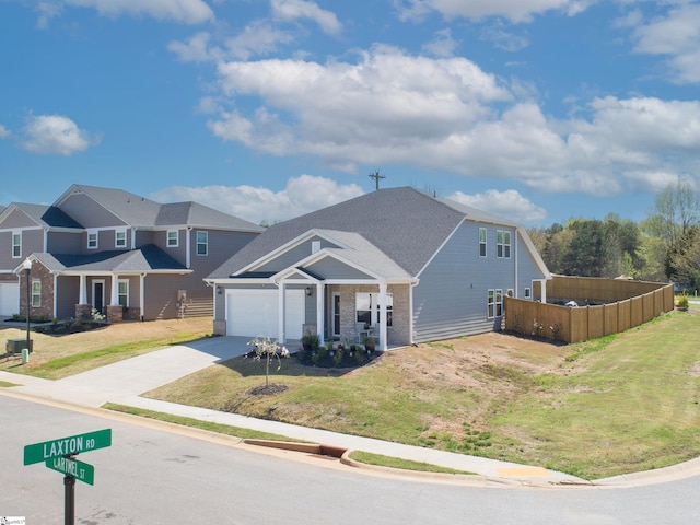 view of front of house featuring an attached garage, concrete driveway, a front yard, and fence