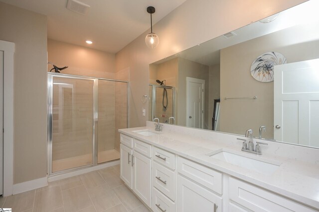 full bathroom with double vanity, a shower stall, tile patterned floors, and a sink