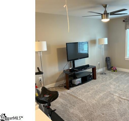 carpeted living area with baseboards and a ceiling fan