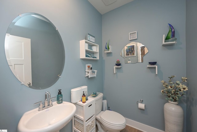 bathroom featuring toilet, baseboards, and a sink