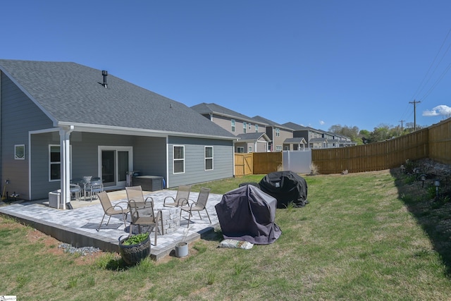 rear view of house with a patio, a fenced backyard, a lawn, and a shingled roof