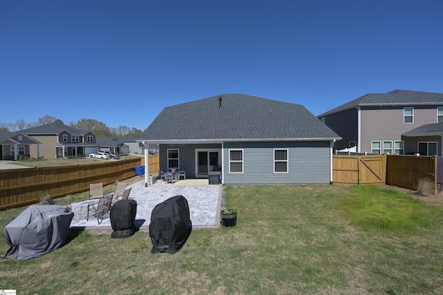 back of house featuring a patio, a fenced backyard, a shingled roof, a lawn, and a residential view