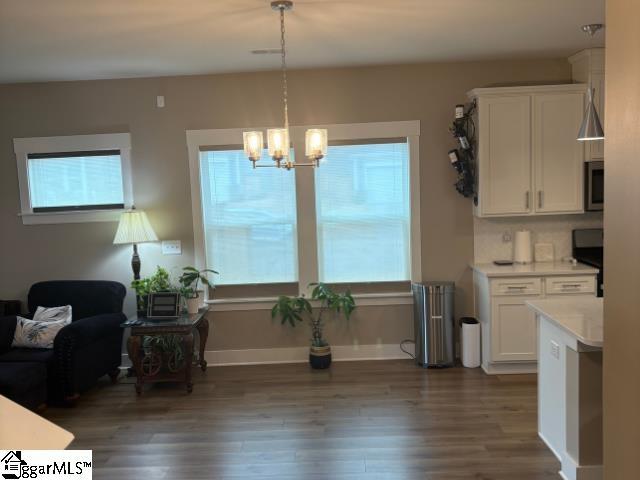 interior space featuring white cabinetry, stainless steel microwave, light countertops, and dark wood-type flooring