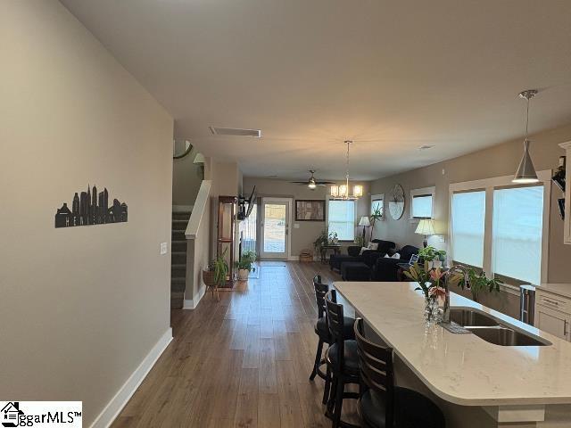 kitchen featuring visible vents, baseboards, dark wood-style flooring, a sink, and hanging light fixtures