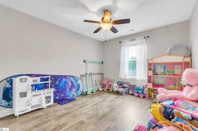 playroom with baseboards, wood finished floors, visible vents, and ceiling fan