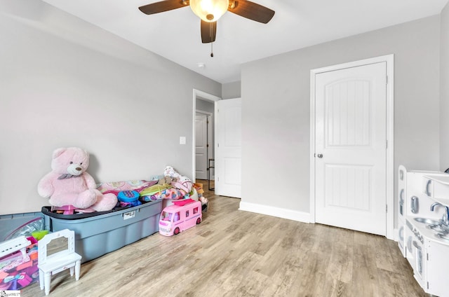 game room with light wood finished floors, ceiling fan, and baseboards