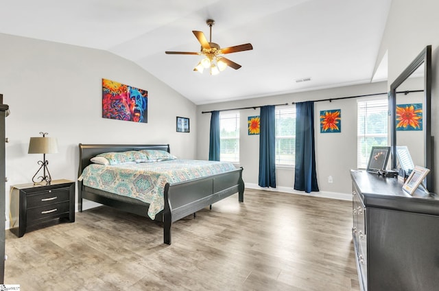 bedroom featuring light wood-type flooring, visible vents, lofted ceiling, and baseboards