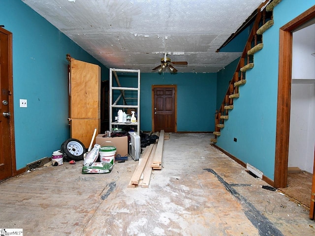 interior space with baseboards, stairs, and ceiling fan