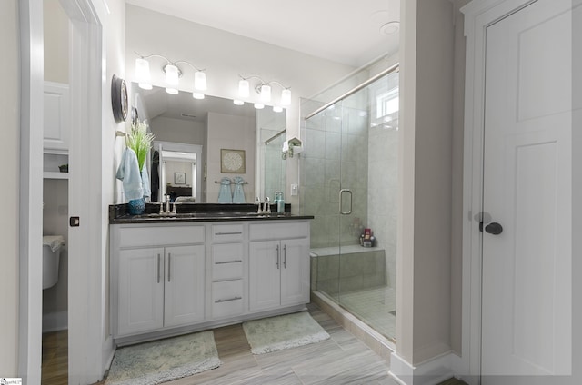 bathroom with a sink, a stall shower, and double vanity