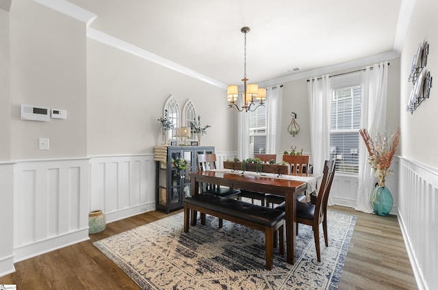 dining area with a wainscoted wall, crown molding, wood finished floors, and visible vents