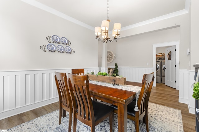 dining area featuring wood finished floors, wainscoting, washer and dryer, crown molding, and a notable chandelier