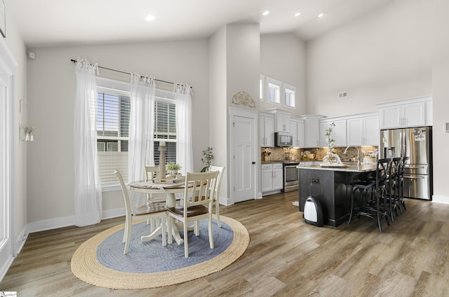 kitchen with a kitchen bar, white cabinets, light wood-type flooring, and stainless steel appliances