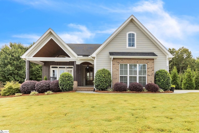 view of front of property with a front lawn, brick siding, and roof with shingles