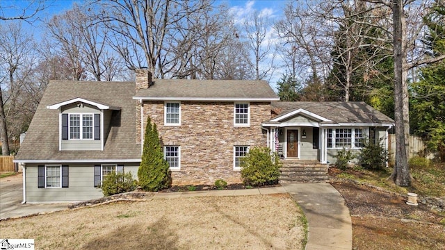 tri-level home featuring stone siding, roof with shingles, and a chimney